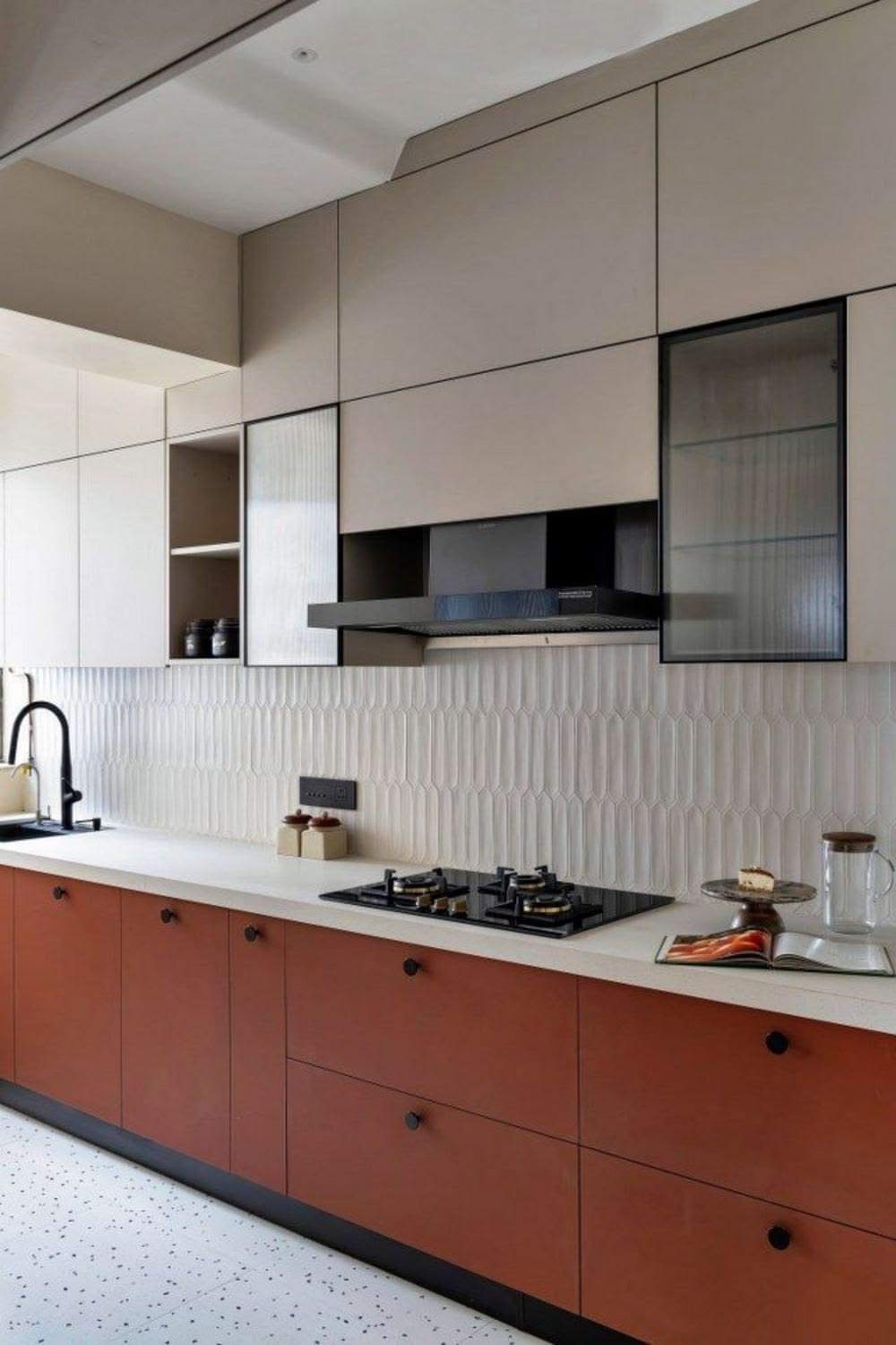 Kitchen with terracotta lower cabinetry, cream overhead units and a fluted tile backsplash